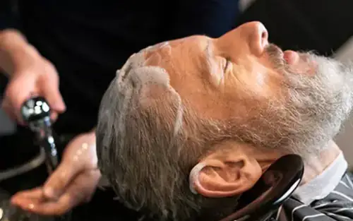 Older client receiving a comfortable shampoo service at Dino's